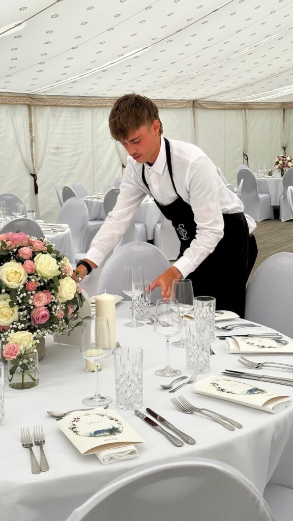 Ein Mitarbeiter von CSL Catering deckt eine Hochzeit in München ein.